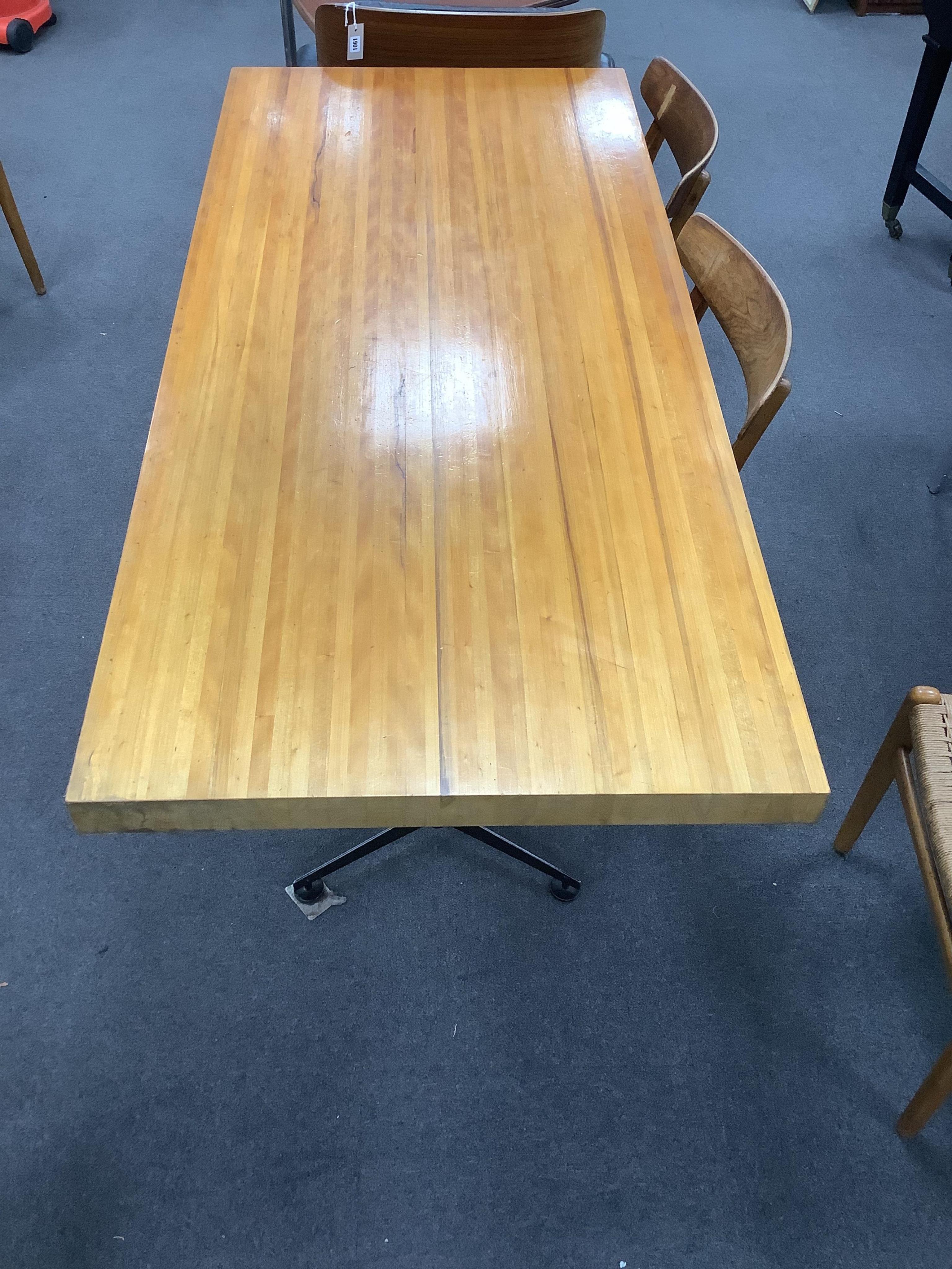 In the manner of Charlotte Perriand, a mid century rectangular maple dining table on twin three prong cast metal end standards, width 179cm, depth 81cm, height 71cm. Condition - fair to good